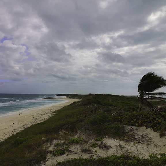 Three guests relaxing in white beach chairs on pristine white sand beach with crystal-clear turquoise Bahamian waters and perfect blue sky - demonstrating the peaceful relaxation and pristine destinations of Breaking Free Sailing charters