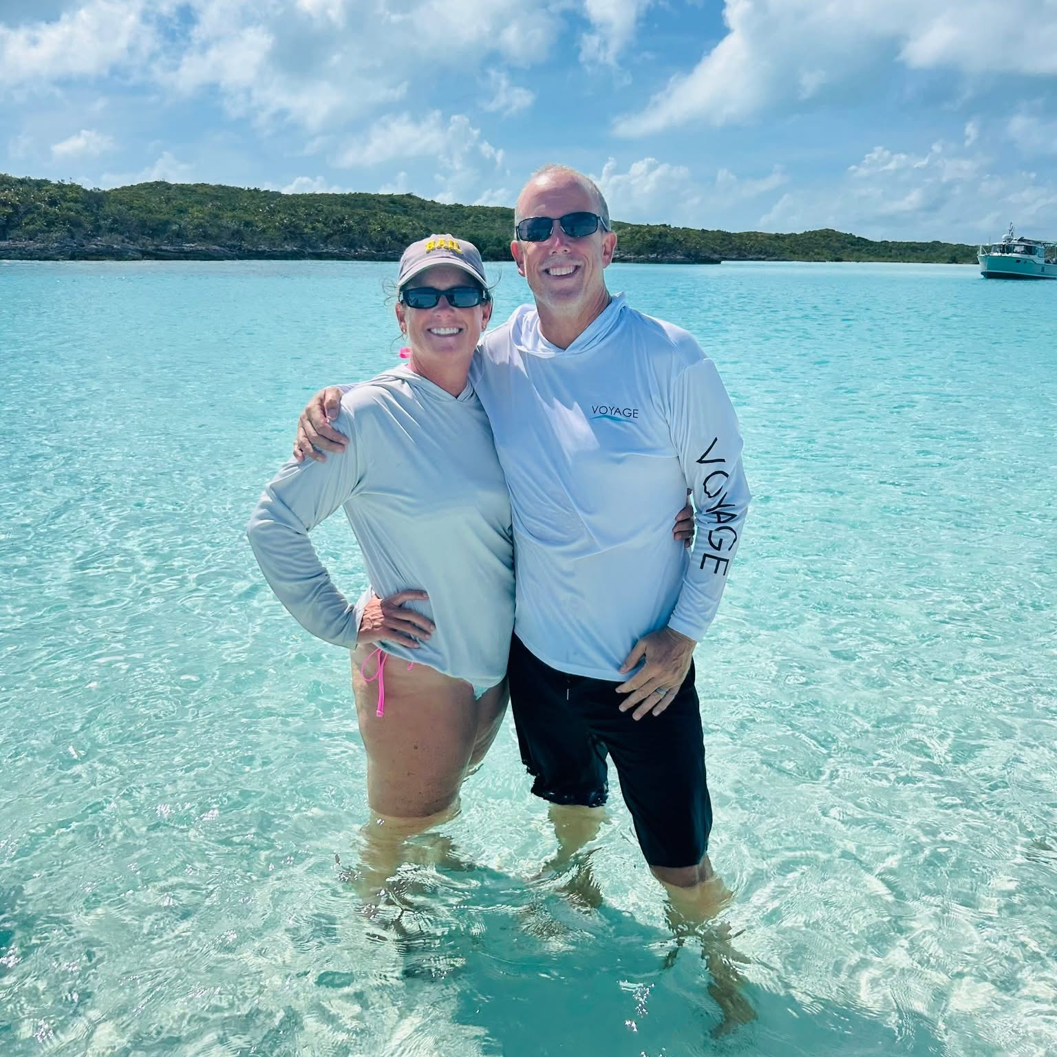 Captain Rob and Admiral Emily on the deck of Bon Bida in the crystal-clear waters of the Exumas, representing the experienced and welcoming crew that makes Breaking Free Sailing charters authentic and memorable